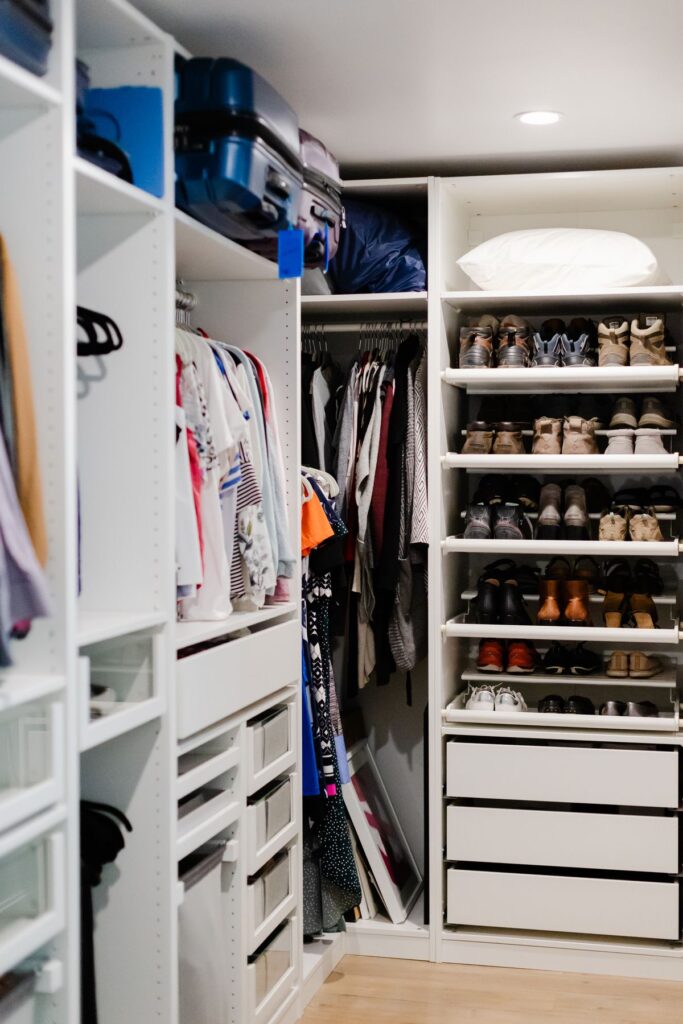 Organized walk-in closet with shelving, hanging rods, and shoe racks