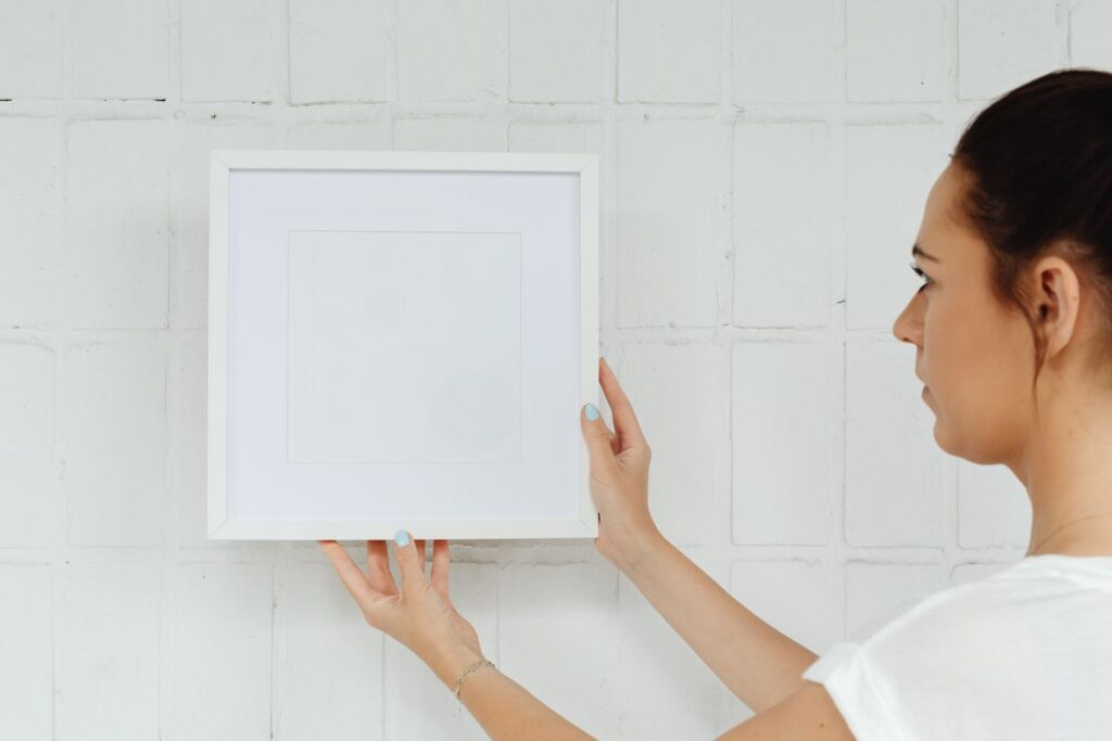 Person carefully hanging and leveling a framed piece on a wall