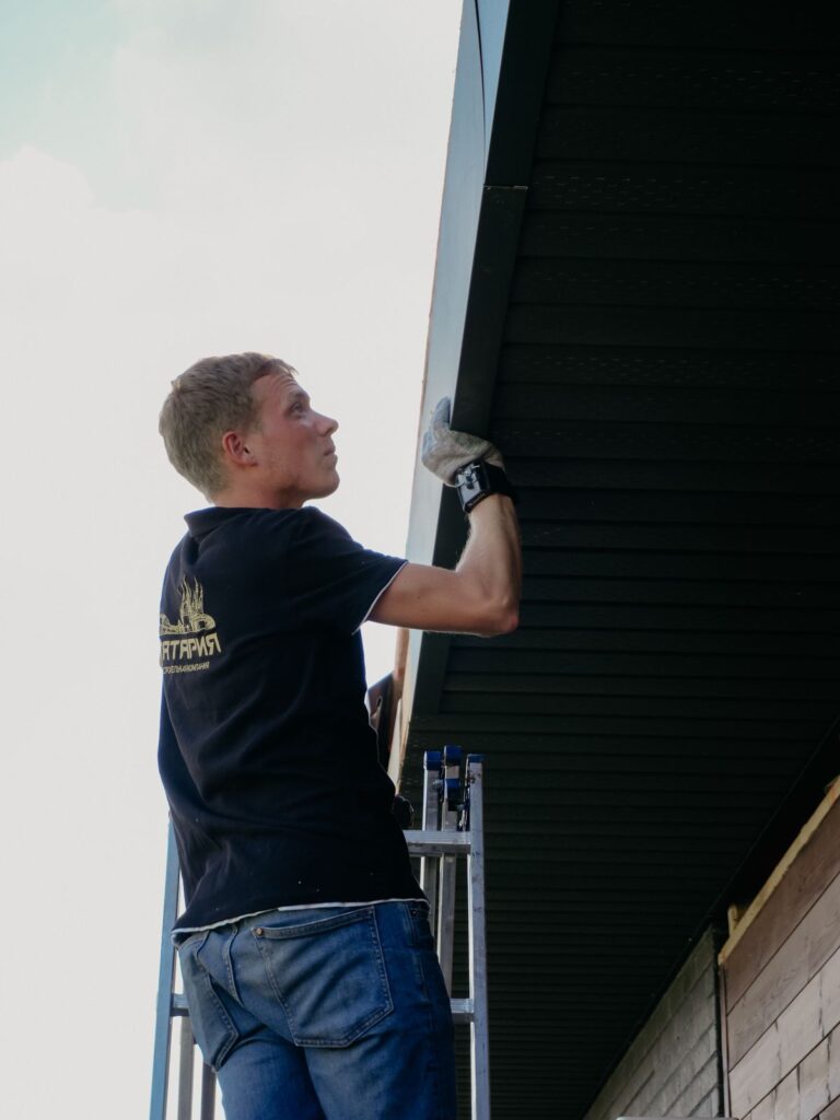 Handyman on a ladder performing exterior home repair