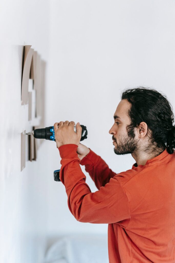 Handyman drilling into a wall to install light carpentry securely
