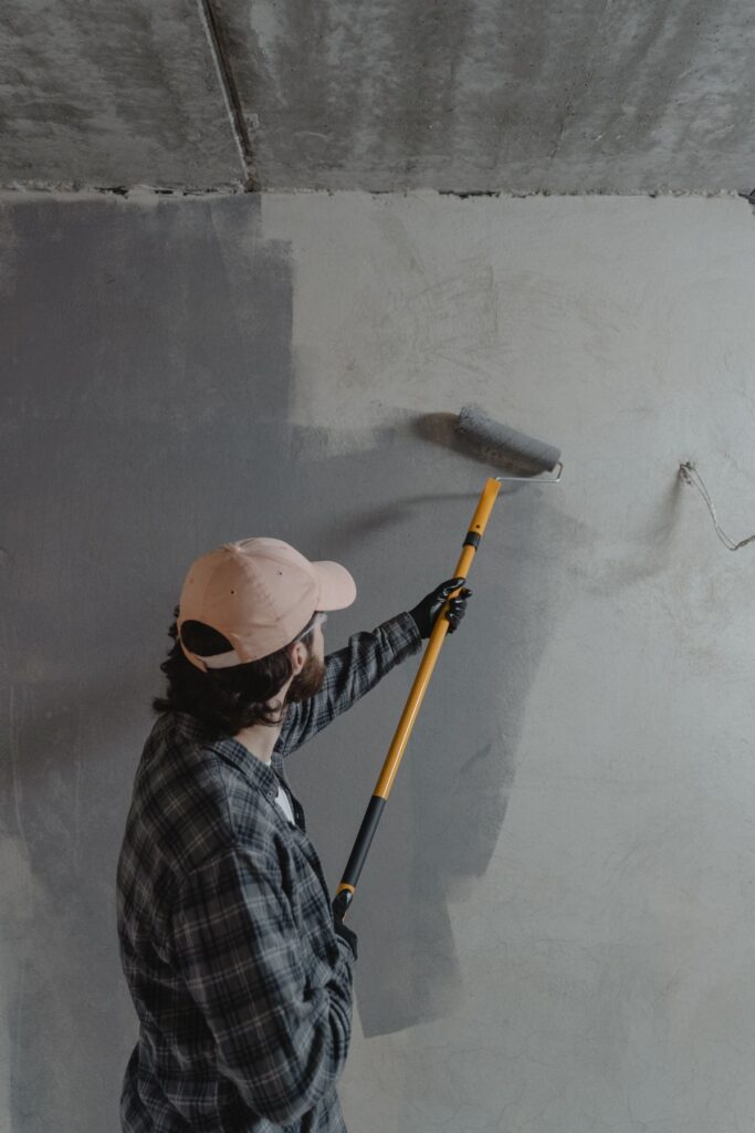 Handyman applying paint to an interior wall with a roller