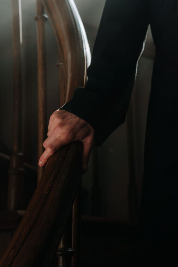 Hand gripping a securely mounted wooden stair handrail