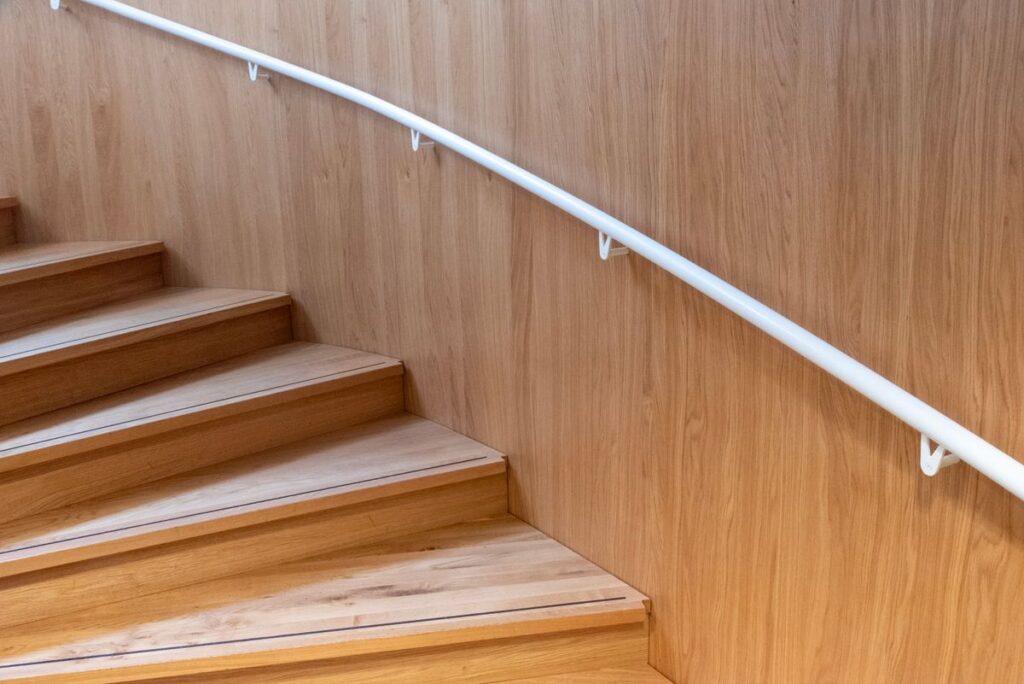 Clean wooden staircase with trim and a mounted handrail