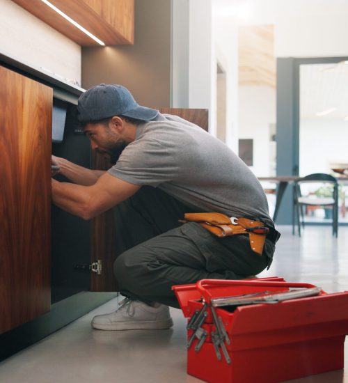 Plumber, man and maintenance in kitchen with tools, repair skills and inspection for quality assurance. Handyman, person and plumbing in home with equipment, fix and check pipeline for restoration.